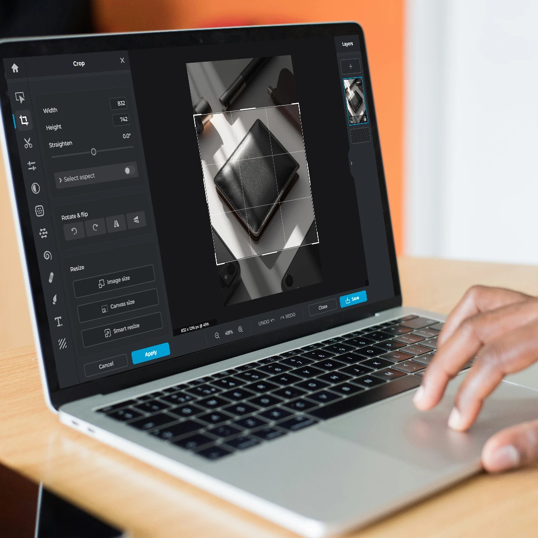 Person using photo editing software on a laptop to crop an image of a wallet.